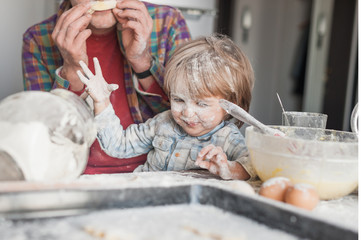 father and child having fun with flour at kitchen