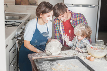 beautiful young family having fun with flour at kitchen while baking
