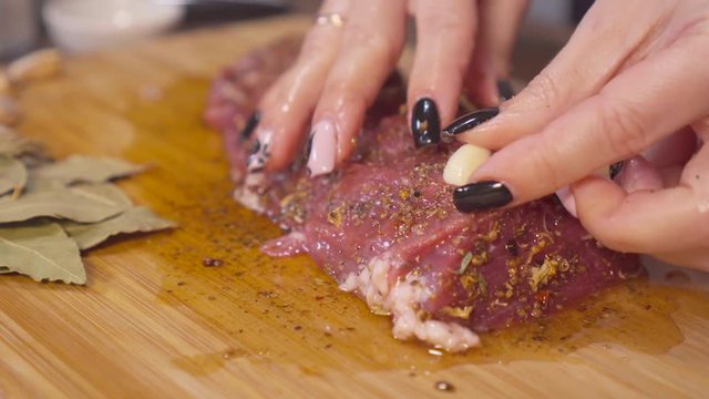 Female hands sprinkle spices and stuff the meat with garlic. Meat in the home kitchen. Making meat