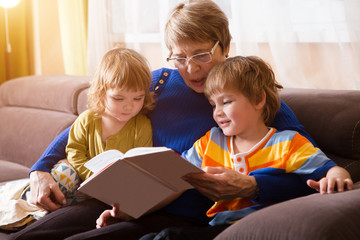 Grandmother reading a tale to her grandson and granddaughter. Family Reading Leisure  