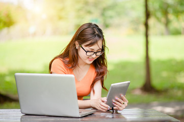 Young beautiful Asian woman working at outdoor park,happy relaxing. owner business woman work  at outdoor park.internet and technology concept.