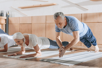 group of senior people doing plank on yoga mats in studio