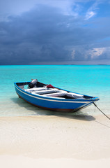 Naklejka na ściany i meble Blue Maldivian boat on the white sand beach