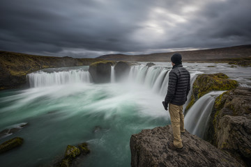 Fototapeta premium Hiker standing at the edge of Godafoss waterfall in Iceland