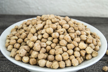 dry chickpea pictures in the bowl over the wooden floor,
ready to cook dried chickpeas dish

