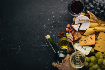 Assortment of cheeses, a bottle of wine, honey, nuts and spices, on a wooden table. Top view. Free space for text.