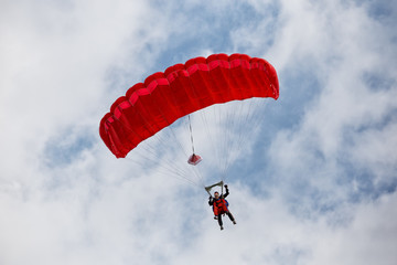 Parachuter descending with a red parachute