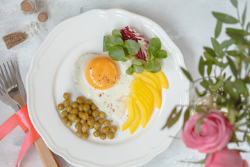 A festive breakfast. Scrambled eggs, green peas and salad, a bouquet of roses. View from above. Valentine's Day concept.