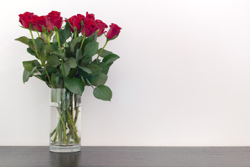 Beautiful red roses in a vase on a wooden surface