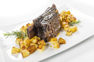Rectangular white plate with cooked beef rib and roasted potatoes