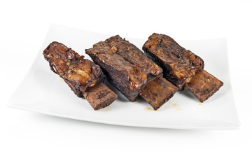 White rectangular plate with three cooked beef ribs