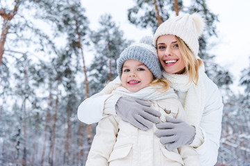 Obraz premium portrait of smiling mother hugging daughter while standing in winter park
