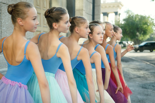 Ballet dancers dancing on street near the theatre. Young ballerinas in color tutus. Ballet feet on the point