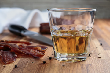 whiskey in a glass and sliced cured meats with spices on oak surface
