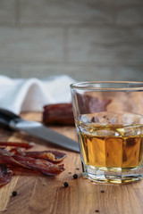 whiskey in a glass and sliced cured meats with spices on oak surface