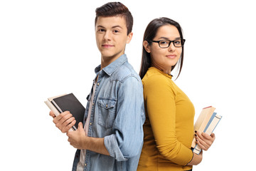 Teenage students with books with their backs against each other