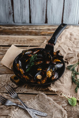 close-up view of delicious fried mussels with shells on frying pan and forks on table