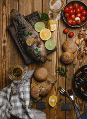 Top view of assorted seafood and baked fish with bread, tomatoes and white wine on wooden table