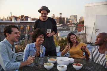 Six adult friends enjoying a party on a rooftop, close up