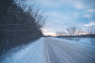Obraz premium Winter snowy road landscape evening out of town.