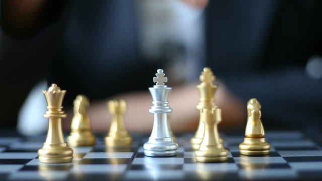 Close up shot hands of man and business woman moving gold king chess to kill silver king chess on chess board game for winner and loser business challenge metaphor and business competition concept