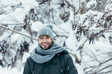 portrait of cheerful young man looking at camera on winter day in park