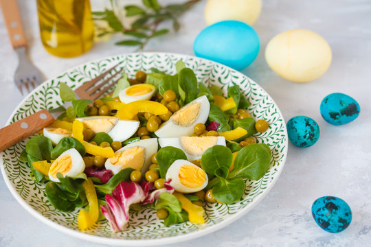 Spring Easter salad with chicken and quail eggs, corn salad, pepper, green peas, painted eggs. Easter concept.