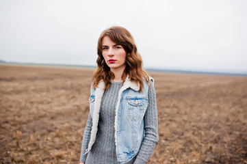 Portrait of brunette curly girl in jeans jacket at field.