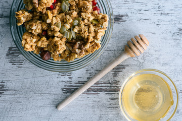 top view of granola and glass bowl with honey on table