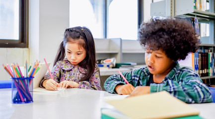 children sitting write homework with yellow pencil in the classroom,education concept.