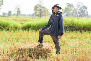 Naklejka na ściany i meble Portrait of Thai farmer standing on rice straw and prepare for livestock
