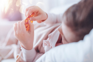 Taking pills. Little girl feeling unwell and lying in her bed while looking at her hands