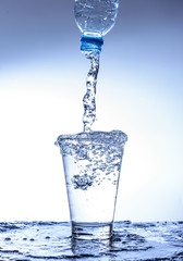 Pouring water and splashing in the glass with reflection on mirror.