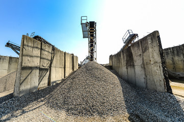 Gravel pit excavation site on a sunny day with industrial machines.