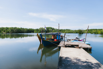 Fototapeta na wymiar Fishing boat moored at the pier near the mangroves. Thaoland.