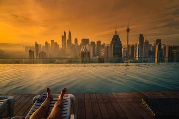 Traveler woman sleep on the sun bed near swimming pool on the roof top of hotel at sunrise in Kuala Lumpur, Malaysia. © nuttawutnuy