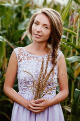 Russian beauty. A portrait of the girl of the blonde against the background of the nature. The woman holds a bouquet with cones in hand.