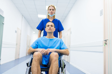 Fototapeta premium female surgeon and male patient in wheelchair in hospital corridor