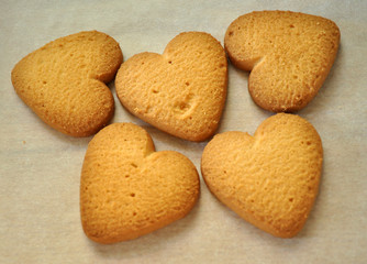 Cookies in form of heart. Baked cookies-hearts on the vintage table. Baking love heart cookies for Valentine day. Gingerbread hearts cookies on white background as Christmas decoration. Love concept.