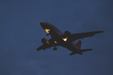 Passenger or cargo plane flies to the dark sky at dusk on the eve of night