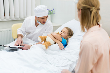 doctor sitting with clipboard and talking with kid patient