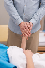 cropped image of husband holding hands with sick wife
