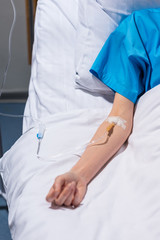 cropped image of sick woman lying on bed with drop counter