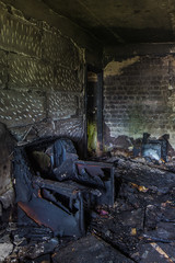 Burnt apartment house interior. Burned chair, charred walls