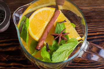 Step by step recipes of citrus tea. Winter Healthy Cold Drink with orange, lemon, cinnamon, mint, anise star and carnation on dark table nbackground. Top view
