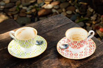 Two empty colorful cups after drinking coffee on a wooden table in a cafe.