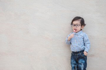Closeup happy asian kid with eyeglasses eating candy on marble stone wall textured background with copy space