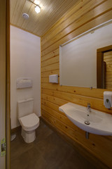 The toilet room with a big mirror, a toilet bowl and a sink