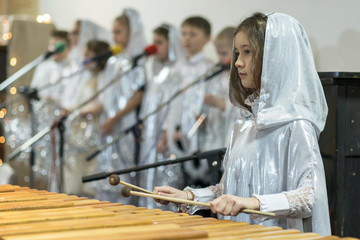 girl is playing a xylophone. White clothes, choir