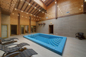 The pool in a blue small tile with chaise lounges